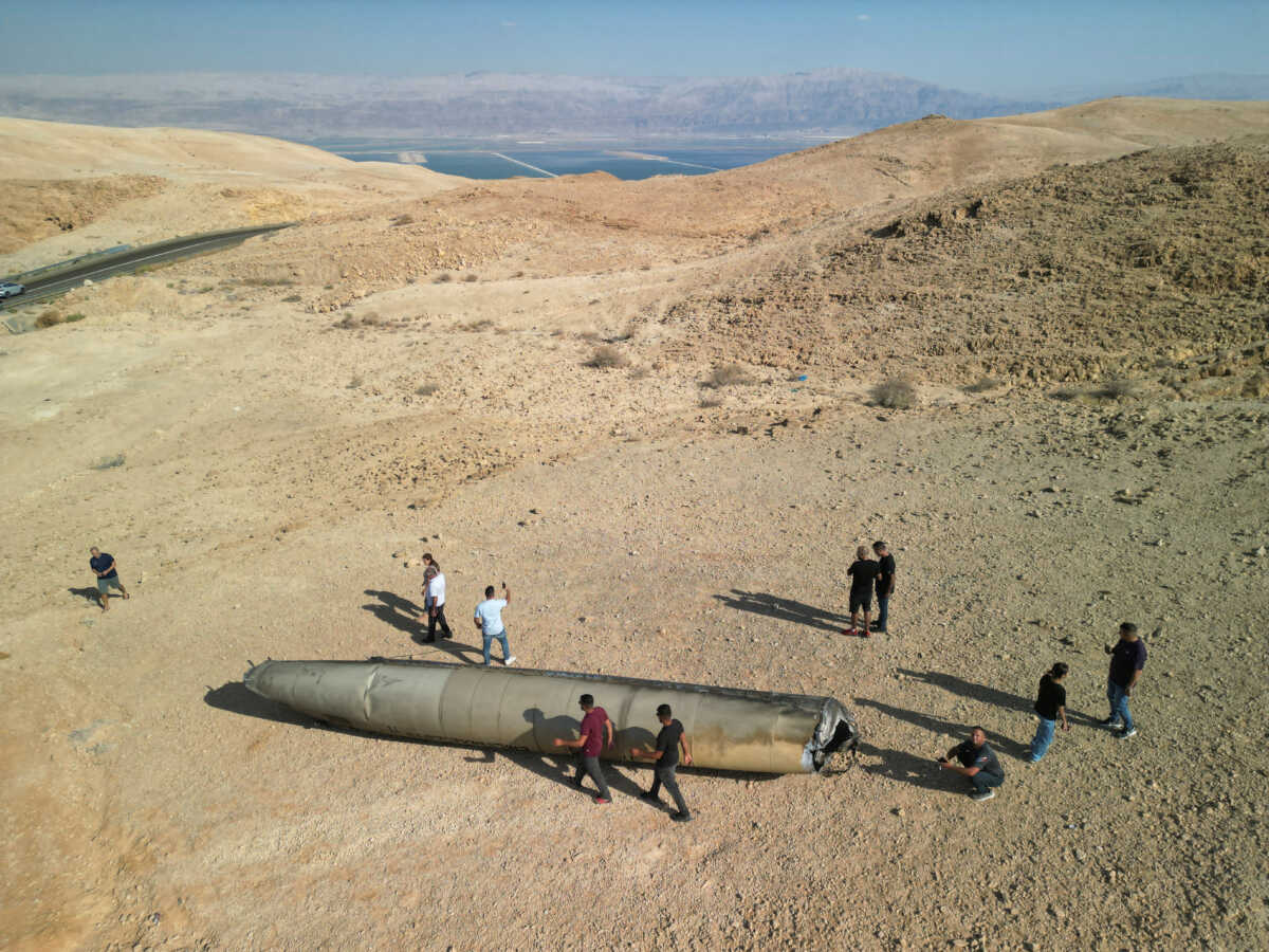 A drone view shows people stand around apparent remains of a ballistic missile lying in the desert, following an attack by Iran on Israel, near the southern city of Arad, Israel October 2, 2024. REUTERS