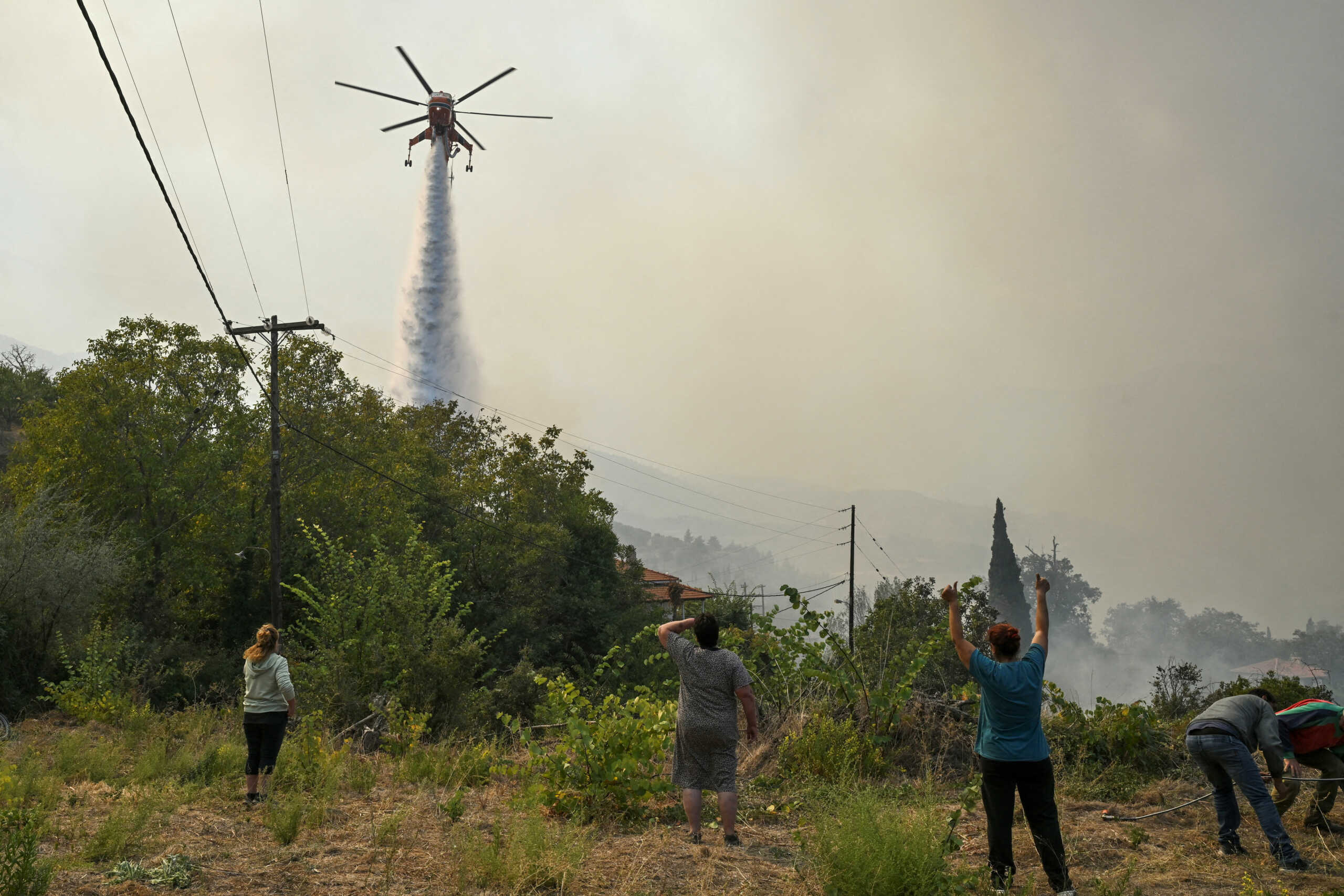 A firefighting helicopter makes a water drop as a wildfire burns in the village of Pyrgos, near Corinth, Greece, September 30, 2024. REUTERS