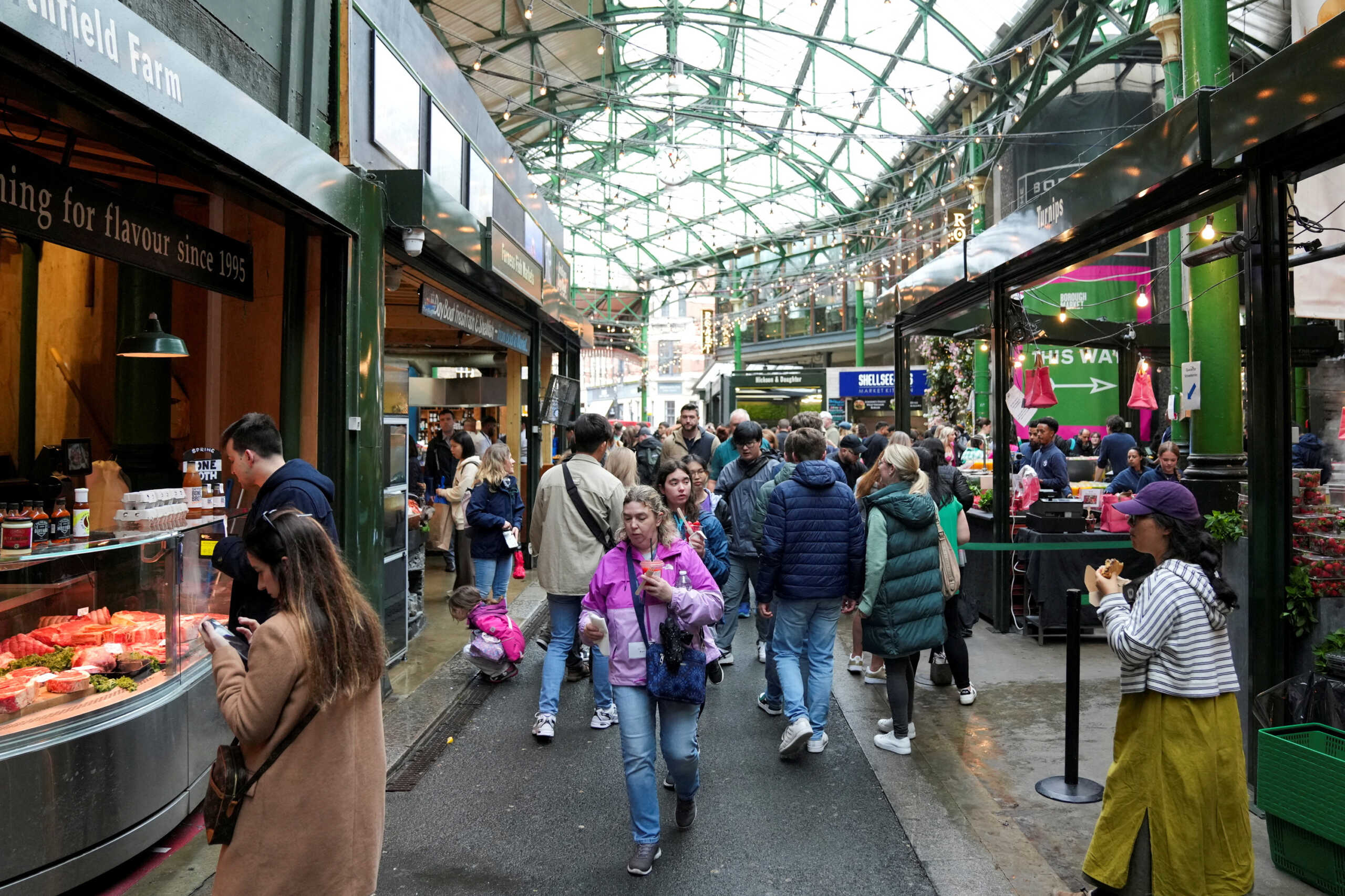 FILE PHOTO: People walk past food stands and market stalls in a Borough Market in London, Britain May 22, 2024. REUTERS