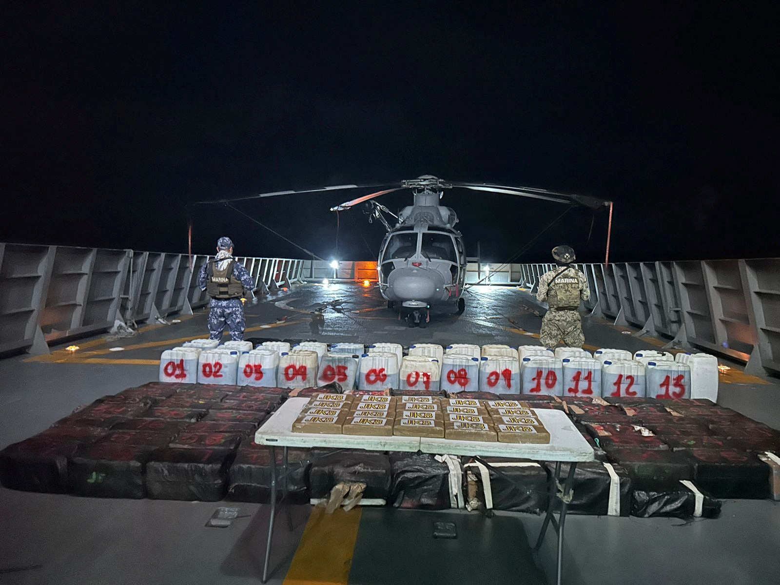 Members of the Mexican Navy stand guard next to packages on display after seizing some 8.4 thousand kilograms of illicit cargo and arresting 23 people in an operation off the country's southwestern Pacific coast, near Lazaro Cardenas, Michoacan, Mexico, in this undated handout photo released on October 18, 2024.  Mexican Navy