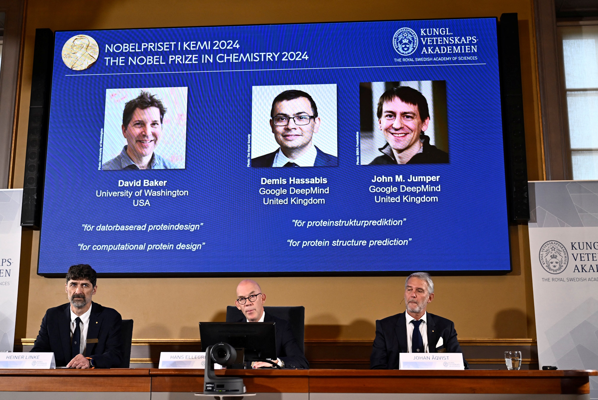 Announcers of the laureates for the Nobel Prize in Chemistry, Johan Aqvist, Hans Ellegren and Heiner Linke, look on as the images of the winners, David Baker (University of Washington, USA), Demis Hassabis (Google DeepMind, UK) and John M Jumper (Google DeepMind, UK) are displayed, in Stockholm, Sweden October 9, 2024. TT News Agency