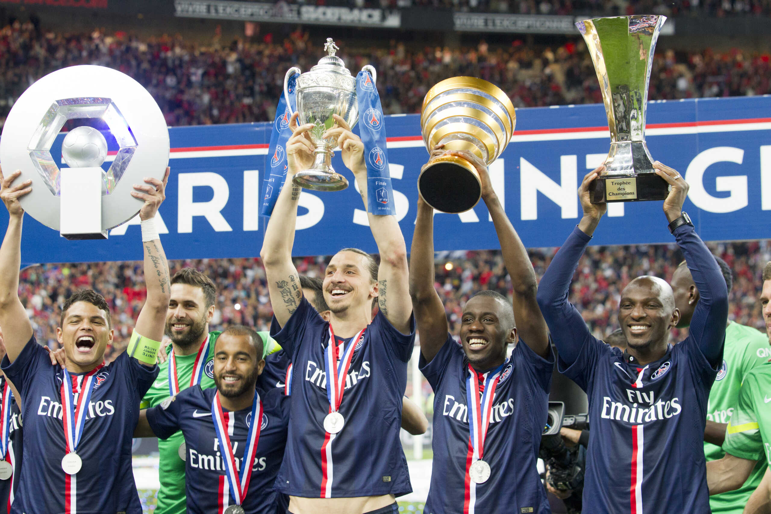 Paris Saint-Germain's (PSG) Brazilian defender Thiago Silva holding up the Ligue 1 trophy, Swedish forward Zlatan Ibrahimovic holding up the French Cup trophy, midfielder Blaise Matuidi holding the French League Cup and defender Zoumana Camara holding the Champions' Trophy as they celebrate after winning the French Cup final football match against Auxerre at the Stade de France stadium in Saint-Denis,  North of Paris, Saturday May 30, 2015. PSG won 1-0. (AP Photo