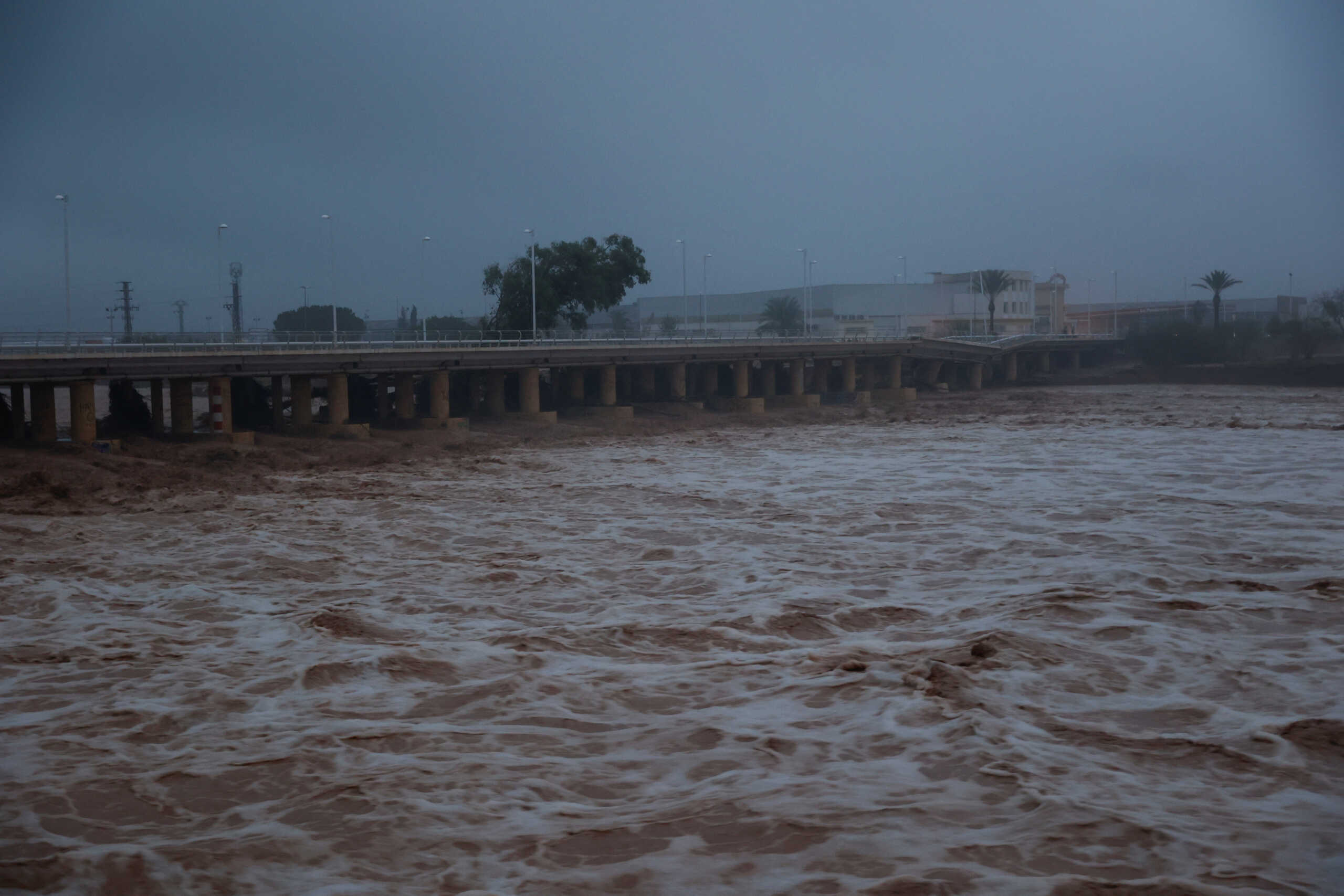River water churns, with a partially collapsed bridge seen in the background, after torrential rains caused flooding in the town of Carlet, Valencia region, Spain, October 30, 2024. REUTERS