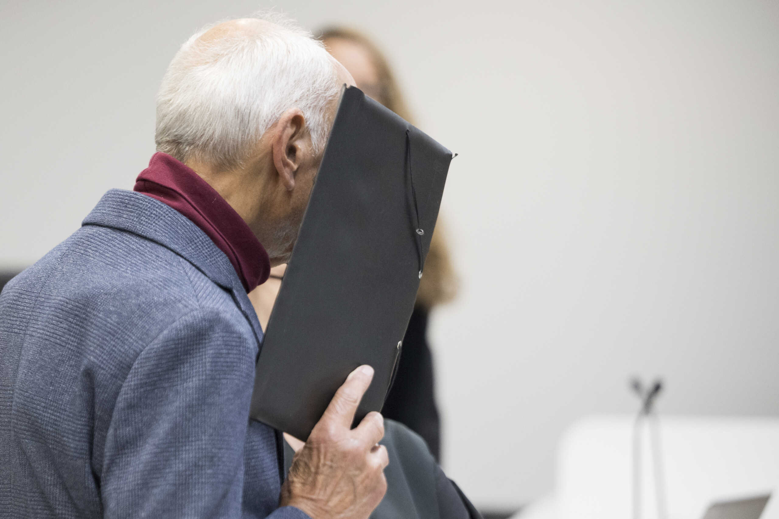 14 October 2024, Berlin: The defendant stands in front of the district court and covers his face before the verdict is announced in the trial against the ex-Stasi employee for murder. The now 80-year-old from Leipzig is alleged to have treacherously shot a Polish citizen at the former Berlin-Friedrichstra'e border crossing in 1974. Photo by: Sebastian Gollnow