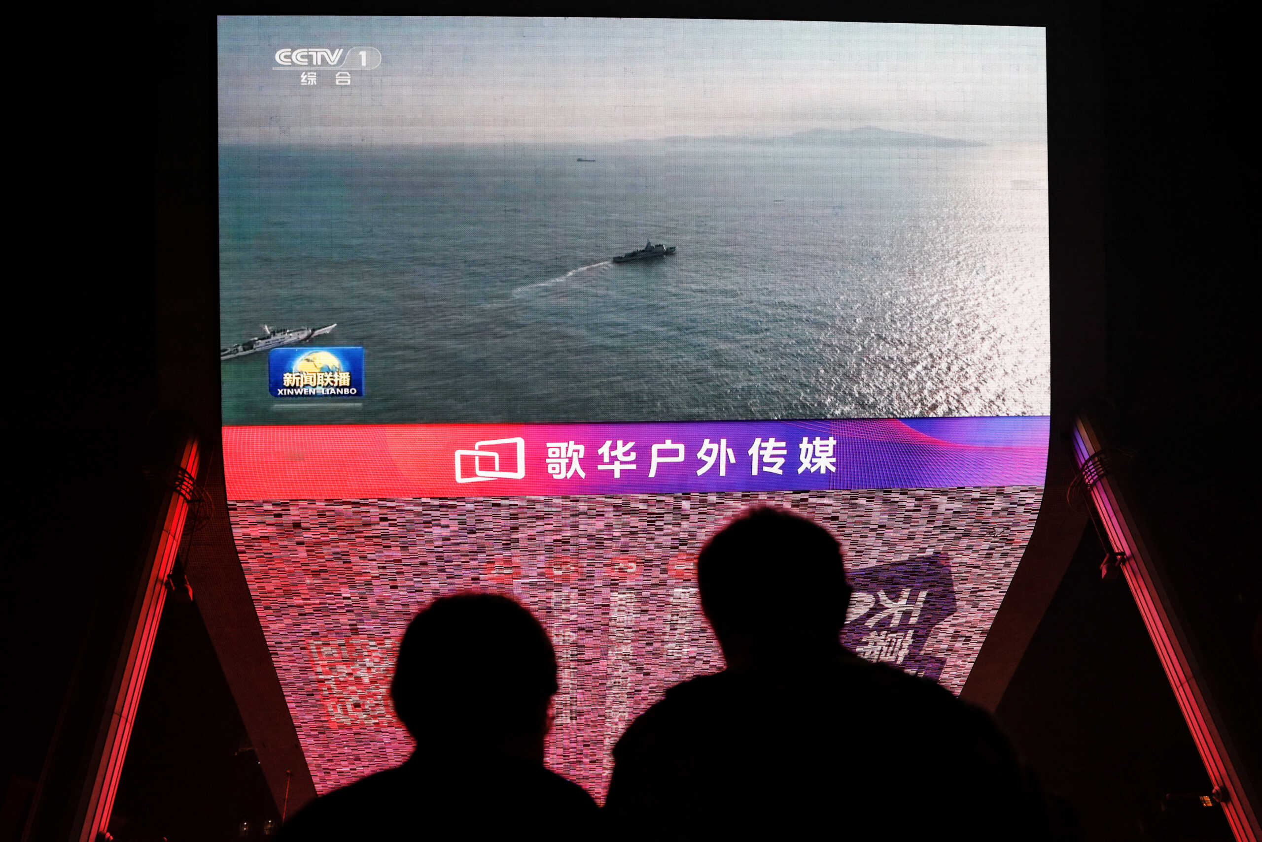People look at a giant screen showing news footage of military drills conducted in the Taiwan Strait and areas to the north, south and east of Taiwan, by the Eastern Theatre Command of the Chinese People's Liberation Army (PLA), in Beijing, China October 14, 2024. REUTERS