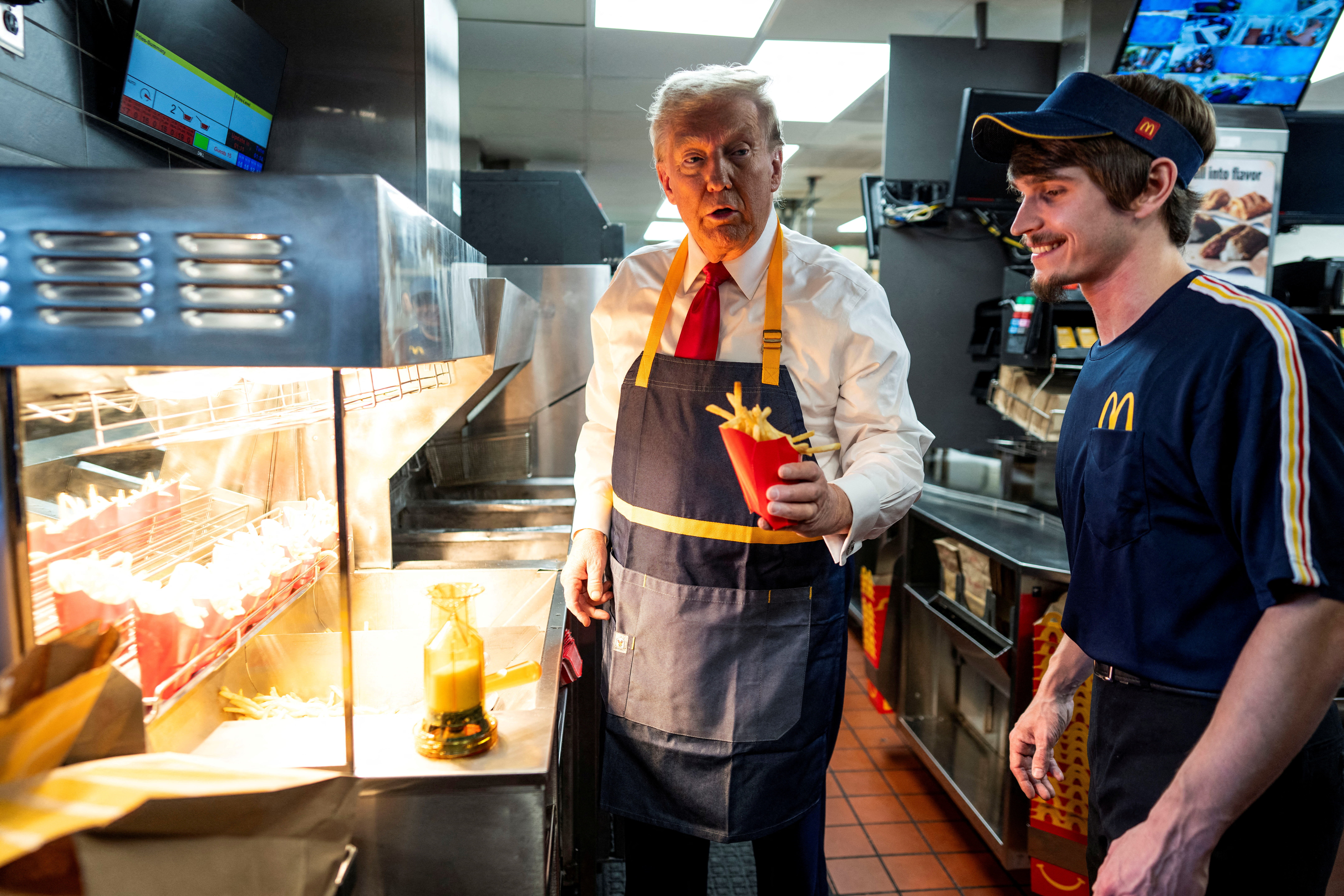 Republican presidential nominee and former U.S. President Donald Trump works behind the counter during a visit to McDonalds in Feasterville-Trevose, Pennsylvania, U.S. October 20, 2024. Doug Mills