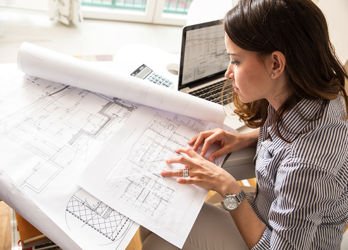 Female architect working at home.She looking blueprints.
