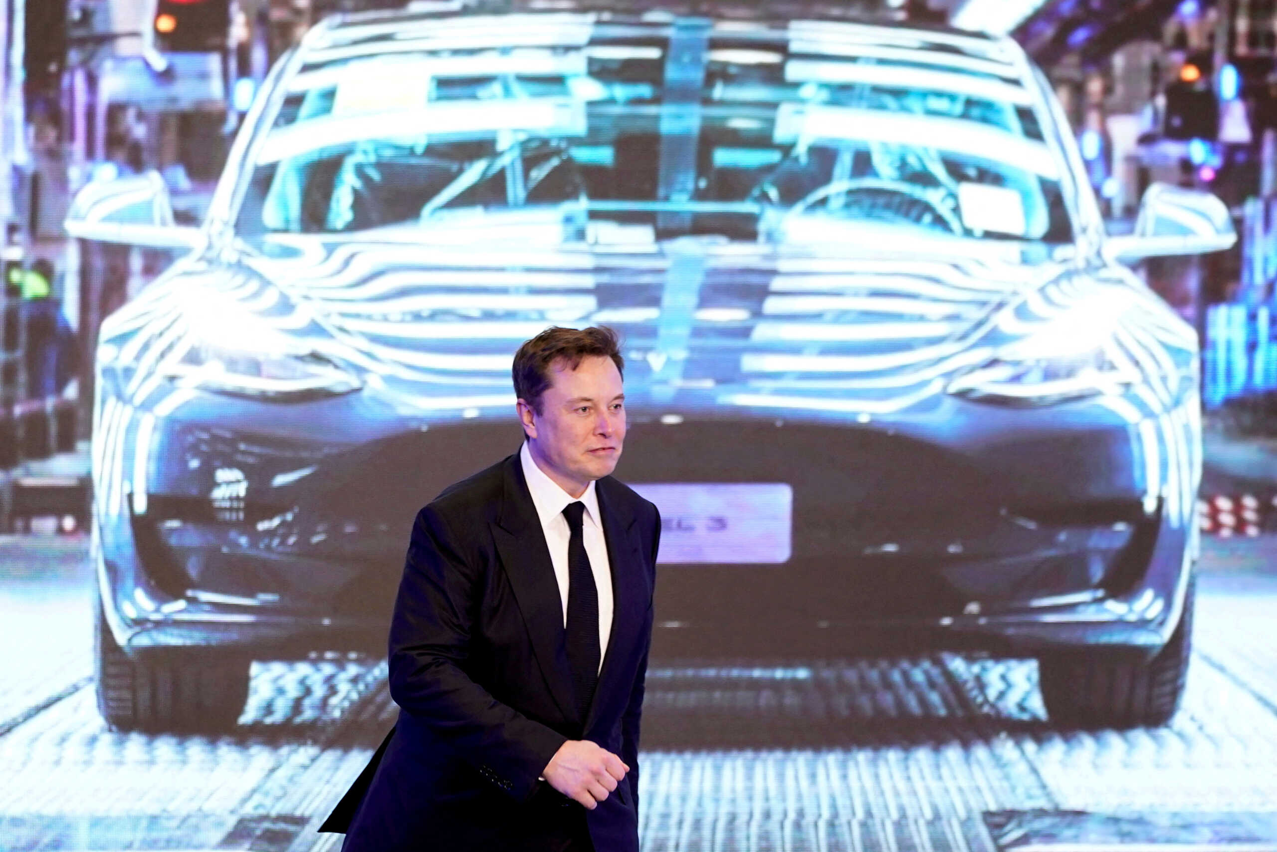 FILE PHOTO: Tesla Inc CEO Elon Musk walks next to a screen showing an image of Tesla Model 3 car during an opening ceremony for Tesla China-made Model Y program in Shanghai, China January 7, 2020. REUTERS