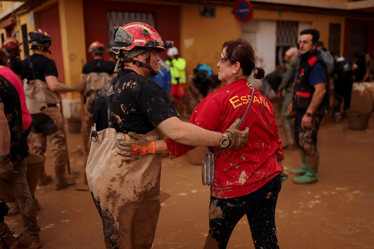 A member of Spain's Military Emergency Unit (UME) stands next to a local woman wearing a Spanish national football team sweatshirt, in the aftermath of floods caused by heavy rains, in Sedavi, near Valencia, Spain, November 3, 2024. REUTERS