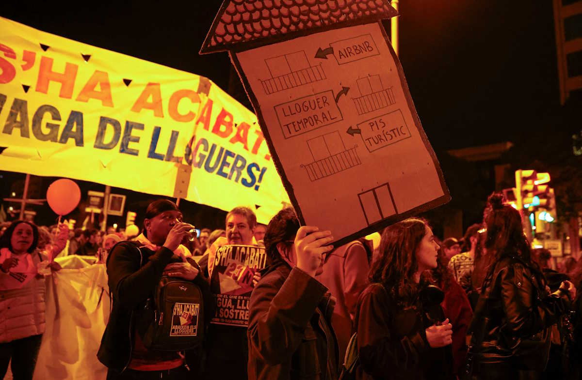 A demonstrator holds a house-shaped sign that reads "from touristic flat to temporary rent to Airbnb" during a protest to demand lower housing rental prices and better living conditions, in Barcelona, Spain, November 23, 2024. REUTERS