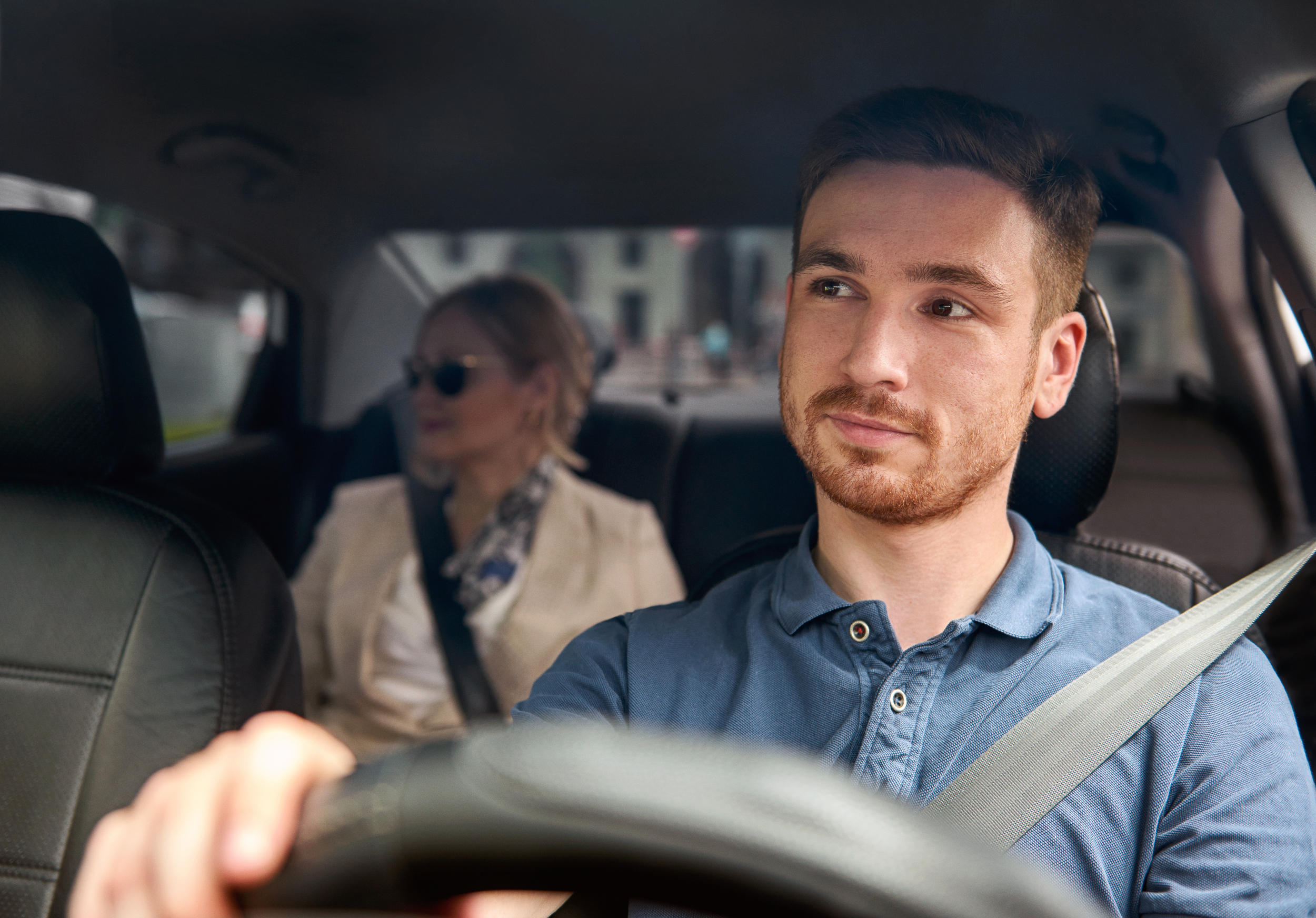 Medium close-up shot of a young male driver transporting a middle-aged female rider