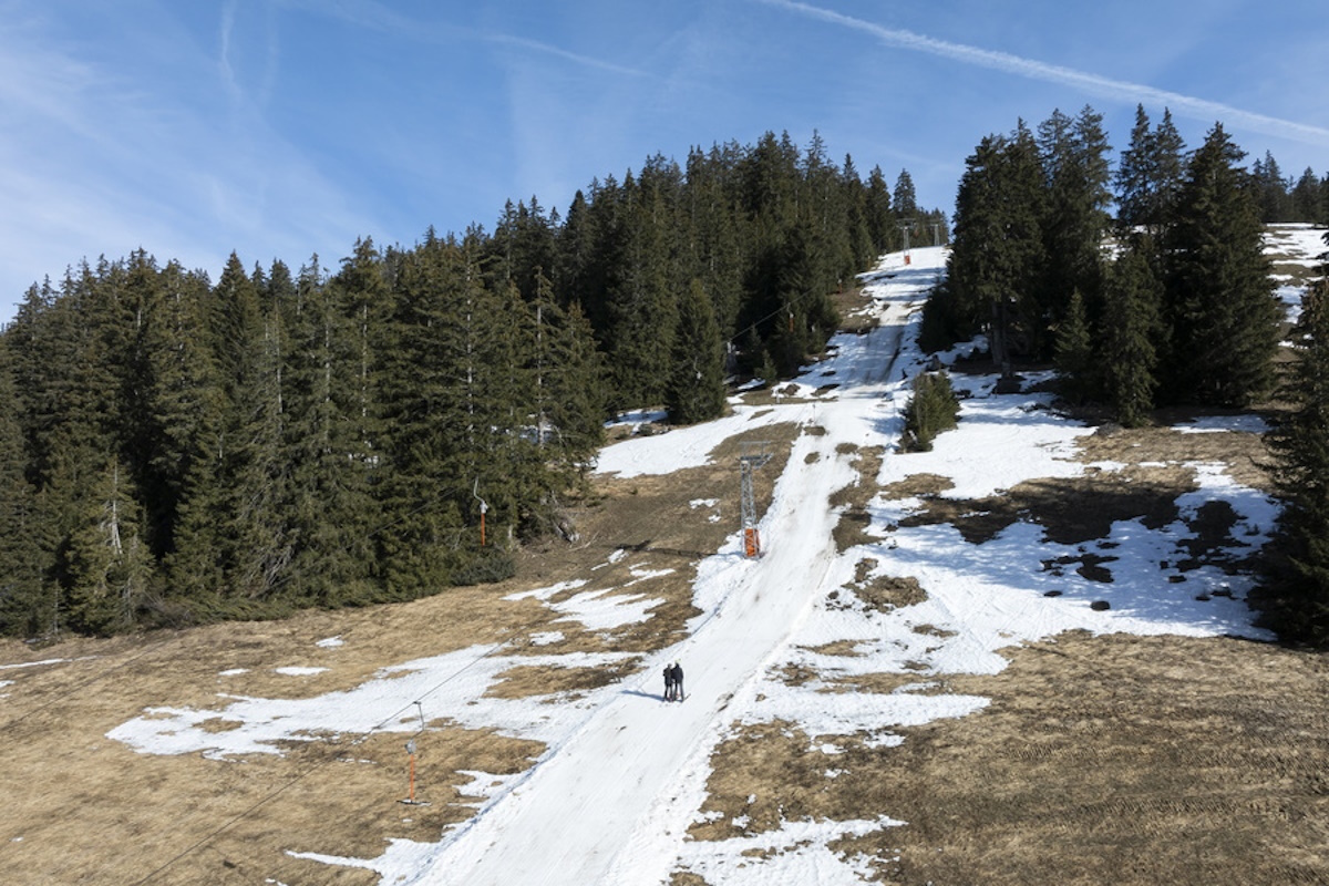 epa11131416 Skiers use a lift on a partially snow-covered ski slope, at an altitude of around 1,450 meters, in the Alpine resort of Les Mosses, in Ormont-Dessous, Switzerland, 06 February 2024. Mild weather in recent days in the Swiss Alps disrupted the activity of alpine ski resorts.  EPA