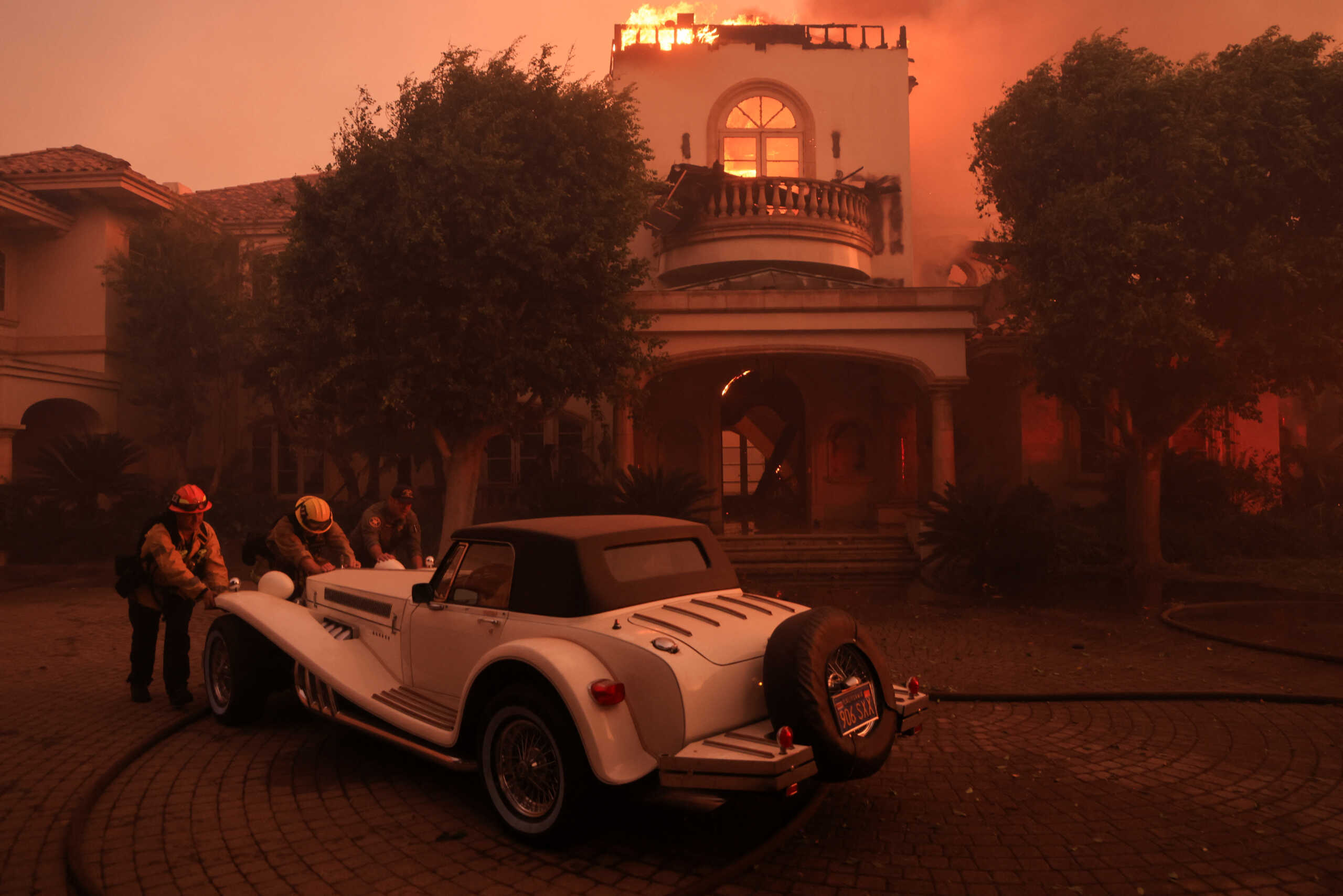 Rescue workers push a vintage car as smoke billows from the Mountain Fire in Camarillo, California, U.S., November 6, 2024. REUTERS