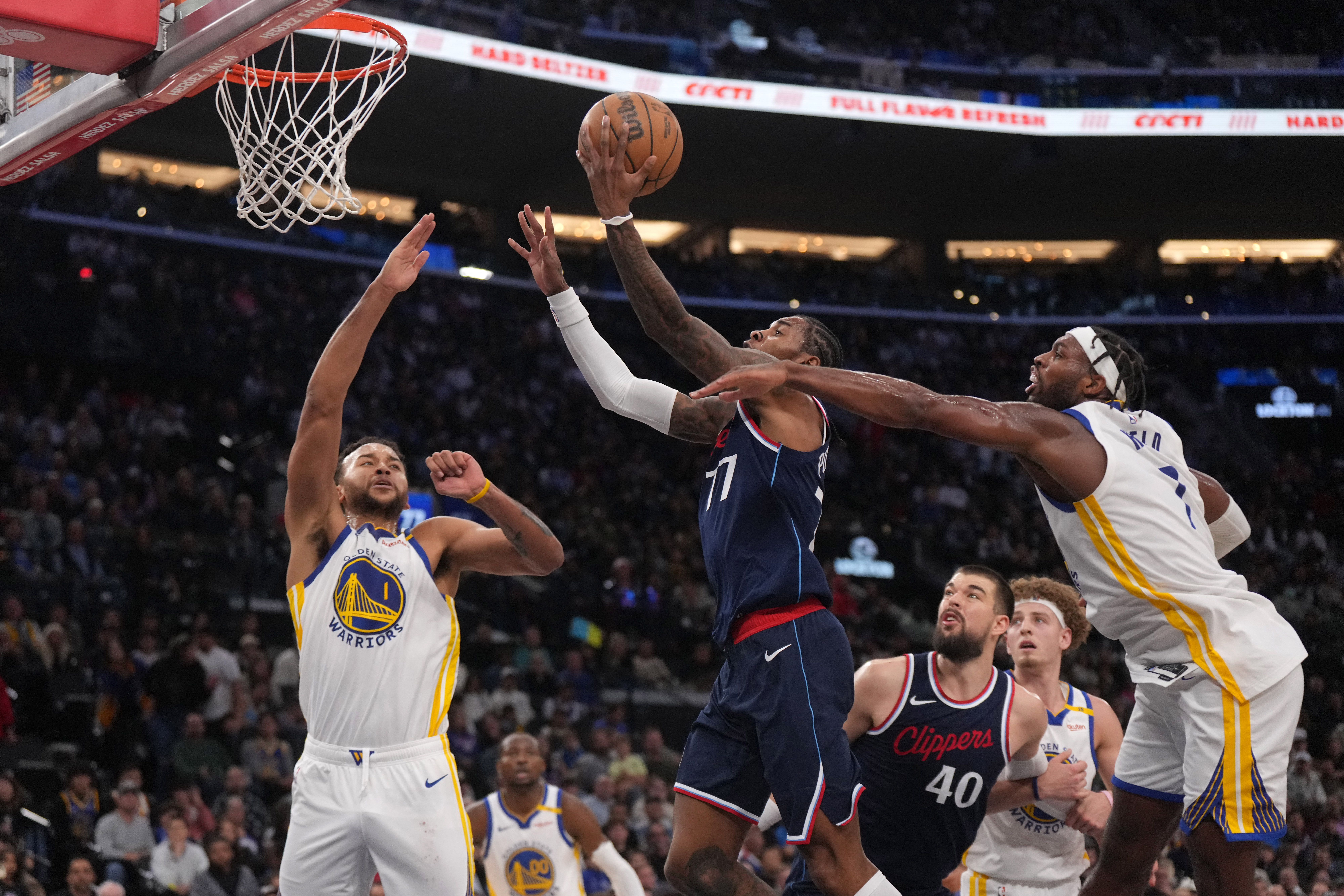 Nov 18, 2024; Inglewood, California, USA; LA Clippers guard Kevin Porter Jr. (77) shoots the ball against Golden State Warriors forward Kyle Anderson (1) and guard Buddy Hield (7) in the second half at Intuit Dome. Mandatory Credit: Kirby Lee-Imagn Images