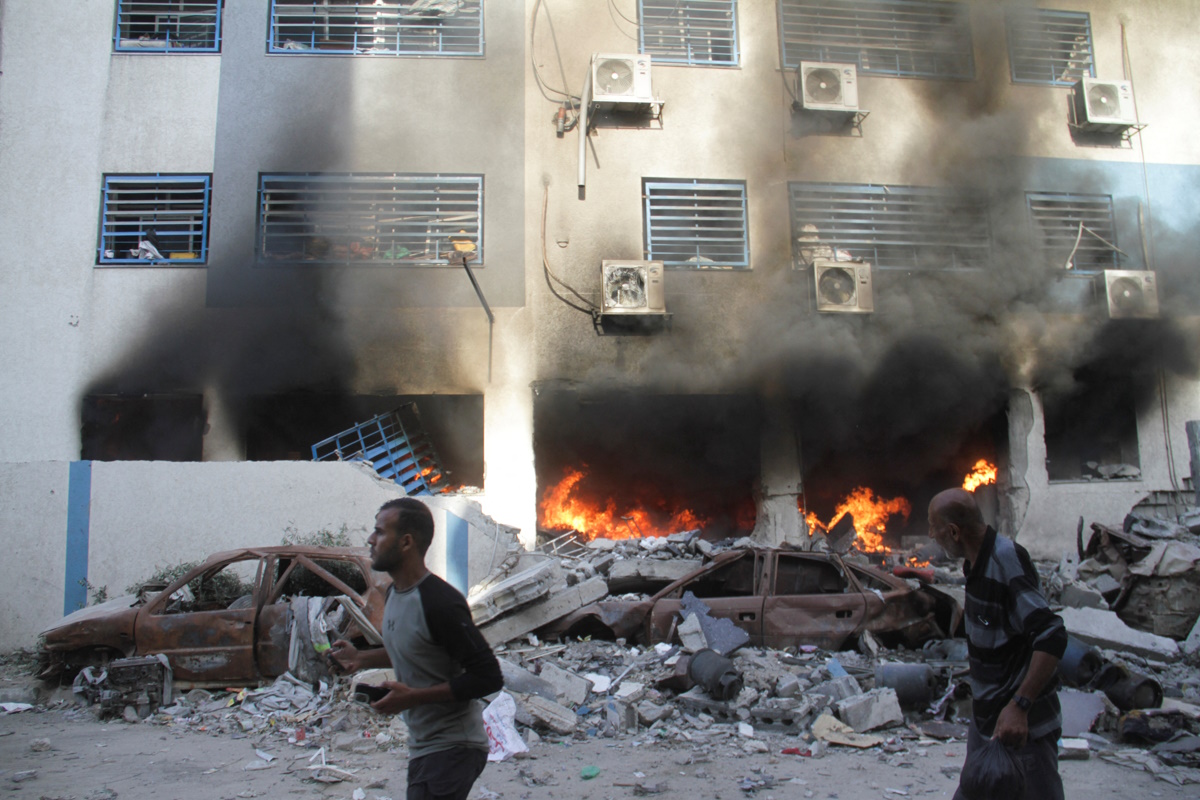 Palestinians walk next to a fire at a school sheltering displaced people, after it was hit by an Israeli strike, in Gaza City November 14, 2024. REUTERS