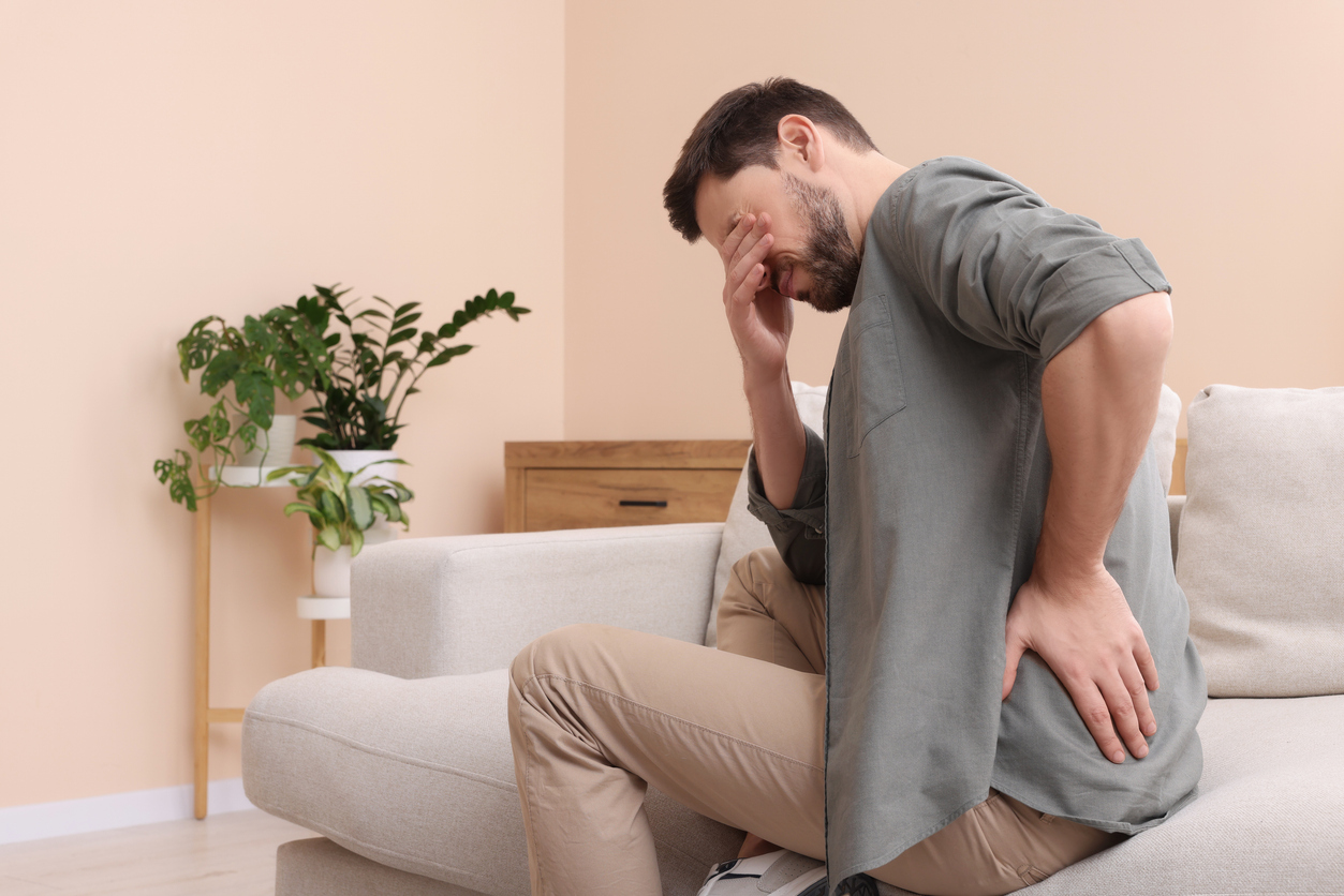 Man suffering from pain in his back at home, space for text. Arthritis symptoms