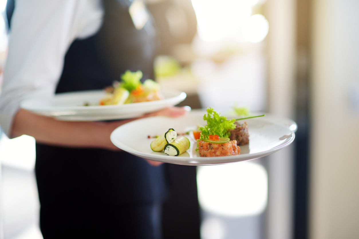 Waiter carrying plates with meat dish on some festive event, party or wedding reception