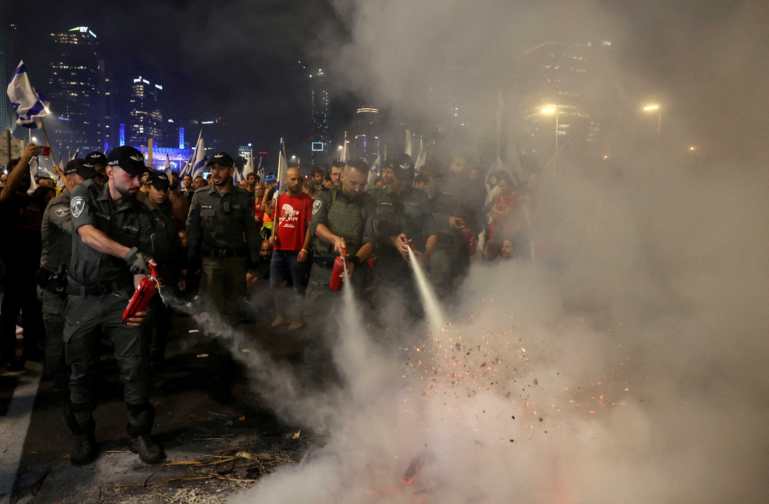 Police officers extinguish a fire as Israelis demonstrate after Israeli Prime Minister Benjamin Netanyahu sacked his defense minister, Yoav Gallant, citing lack of trust, in Tel Aviv, Israel November 5, 2024. REUTERS