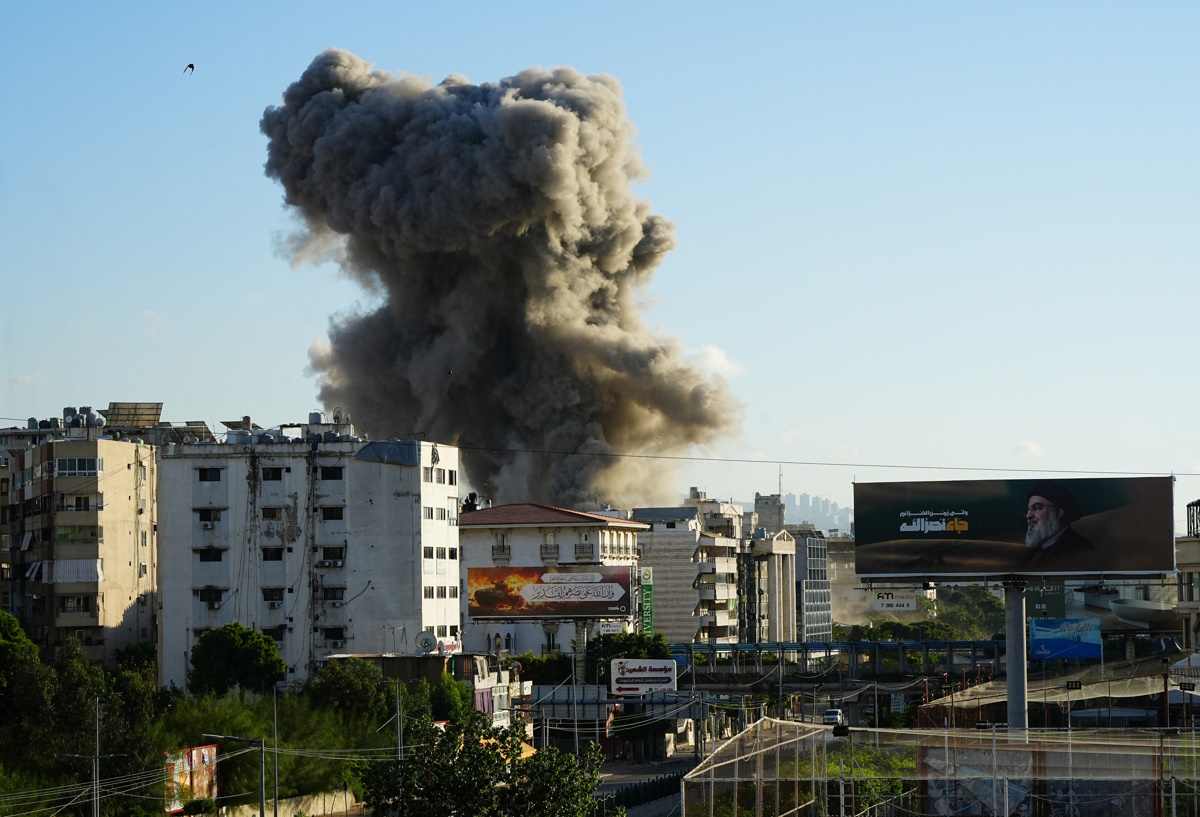A billboard depicting late Hezbollah leader Sayyed Hassan Nasrallah is pictured as smoke billows after an Israeli strike, amid the ongoing hostilities between Hezbollah and Israeli forces, in Beirut's southern suburbs, Lebanon, November 16, 2024. REUTERS