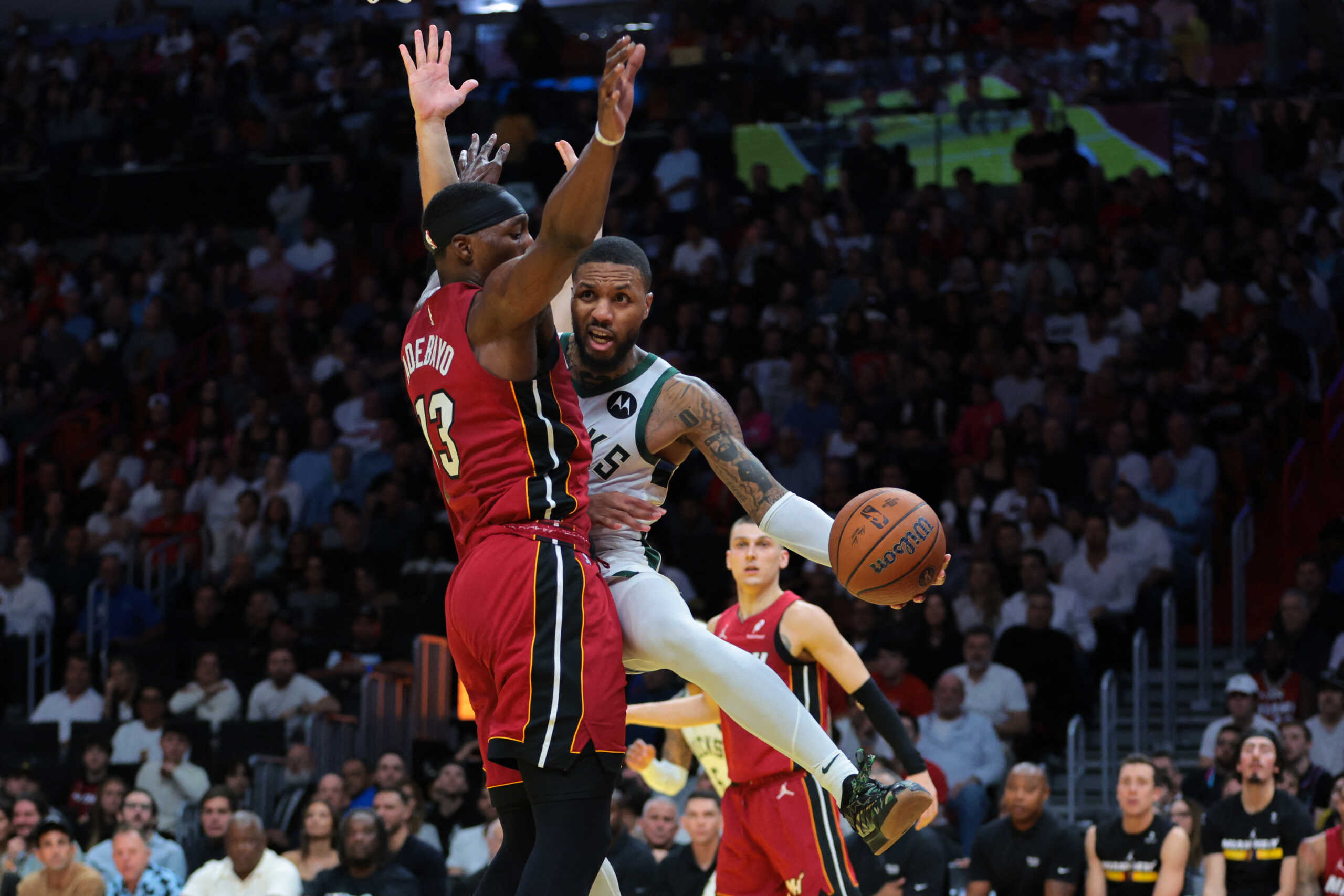 Nov 26, 2024; Miami, Florida, USA; Milwaukee Bucks guard Damian Lillard (0) passes the basketball after driving to the basket against Miami Heat center Bam Adebayo (13) during the fourth quarter at Kaseya Center. Mandatory Credit: Sam Navarro-Imagn Images