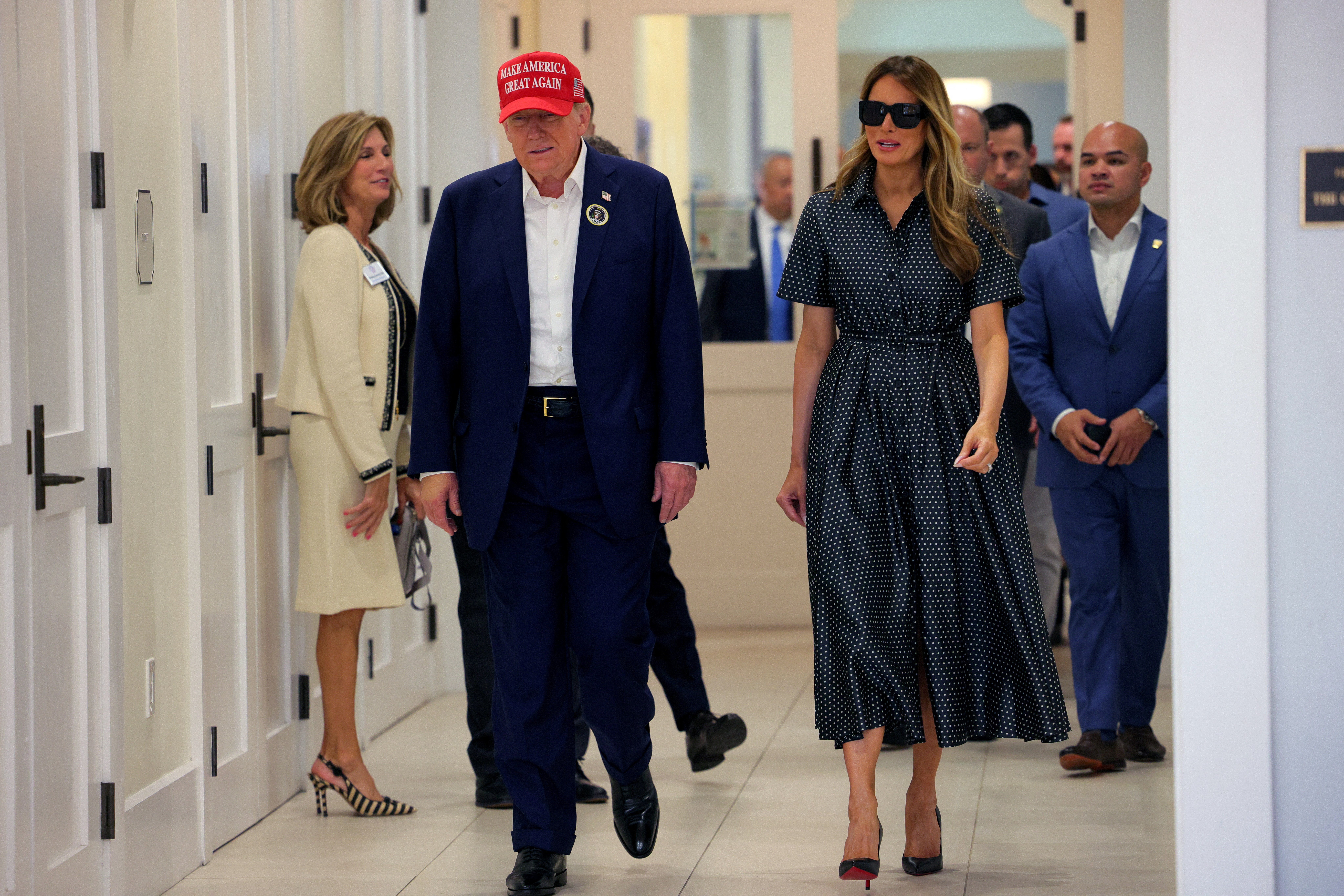 Republican presidential nominee and former U.S. President Donald Trump, flanked by former U.S. first lady Melania Trump, walks at Mandel Recreation Center on Election Day in Palm Beach, Florida, U.S., November 5, 2024. REUTERS