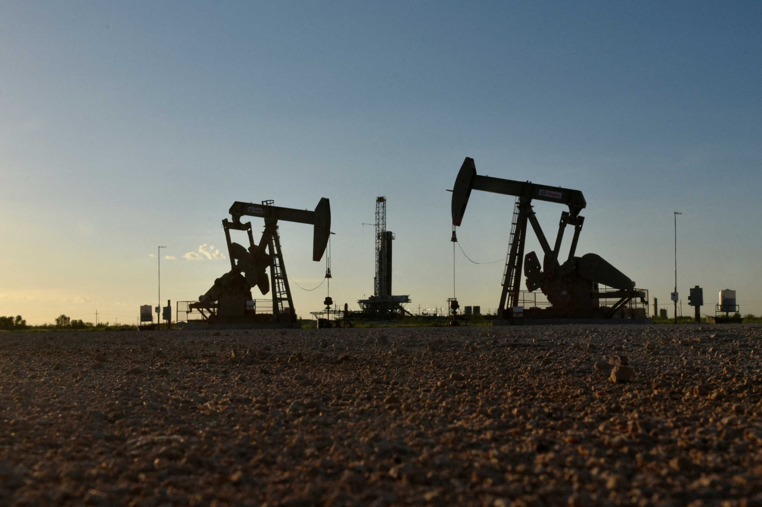 FILE PHOTO: Pump jacks operate in front of a drilling rig in an oil field in Midland, Texas U.S. August 22, 2018. Picture taken August 22, 2018. REUTERS