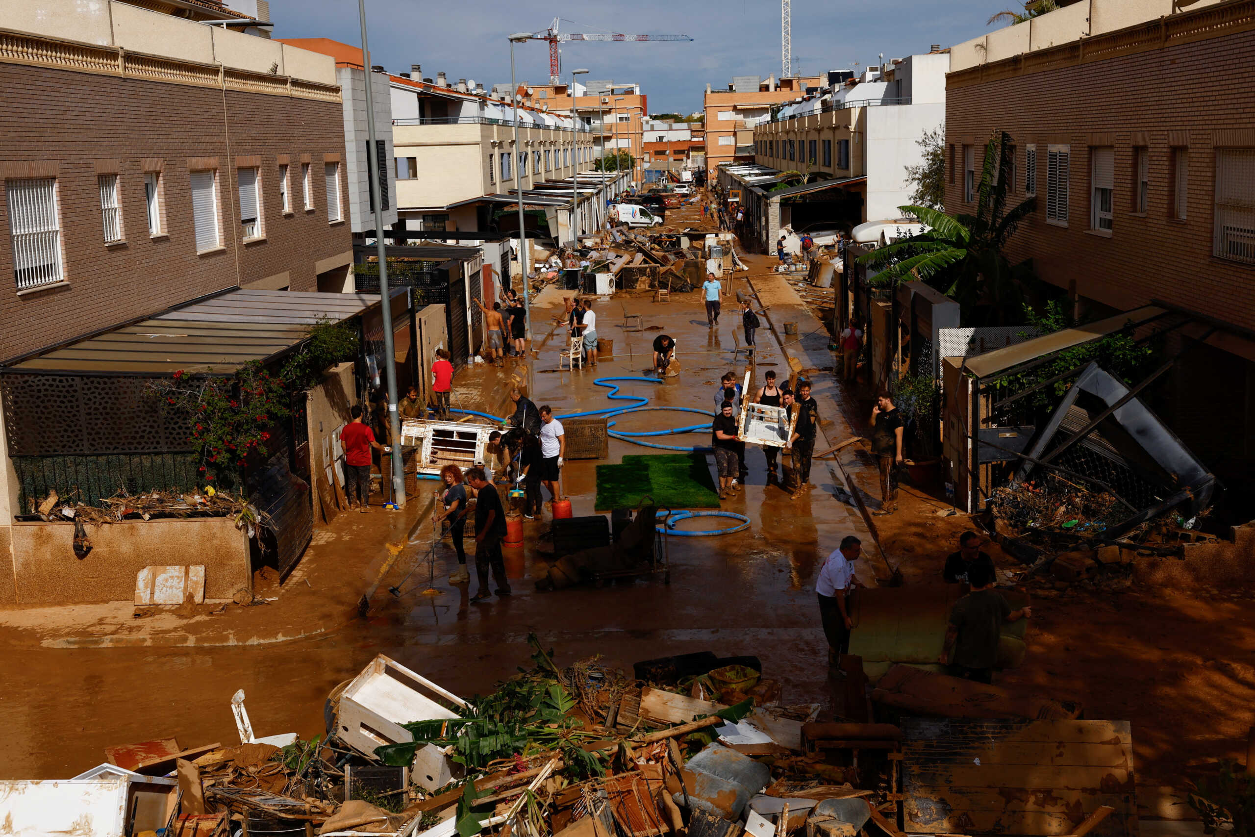 People clean up a mud-covered street after heavy rains in Alfafar, in Valencia, Spain, November 1, 2024. REUTERS