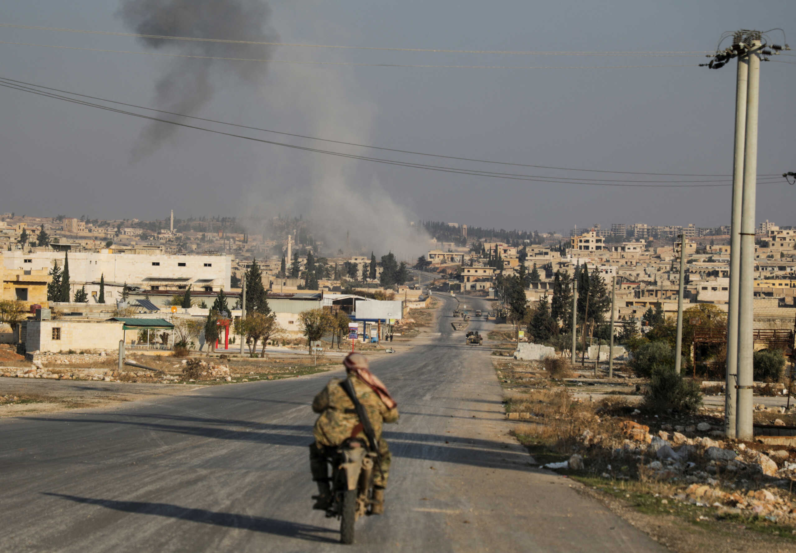 Smoke rises as a member of the rebels led by the Islamist militant group Hayat Tahrir al-Sham drives on a motorbike in al-Rashideen, Aleppo province, Syria November 29, 2024. REUTERS