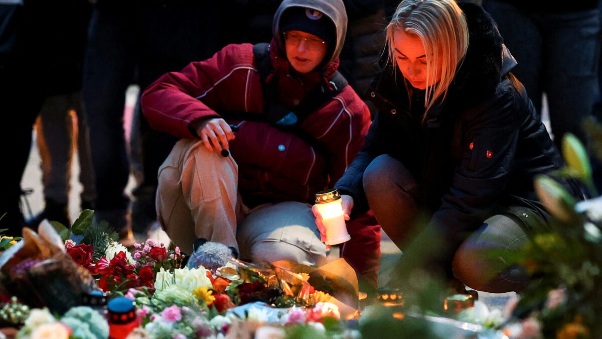 A woman holds a candle as people leave floral tributes to the victims near the site where a car rammed into a crowd at a Magdeburg Christmas market in Magdeburg, Germany December 21, 2024. REUTERS
