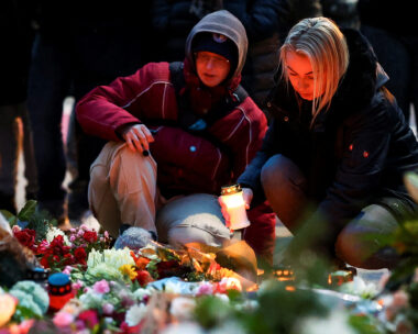 A woman holds a candle as people leave floral tributes to the victims near the site where a car rammed into a crowd at a Magdeburg Christmas market in Magdeburg, Germany December 21, 2024. REUTERS