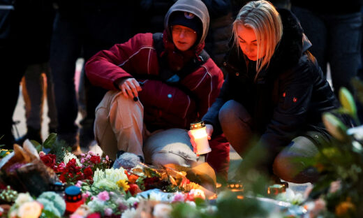 A woman holds a candle as people leave floral tributes to the victims near the site where a car rammed into a crowd at a Magdeburg Christmas market in Magdeburg, Germany December 21, 2024. REUTERS