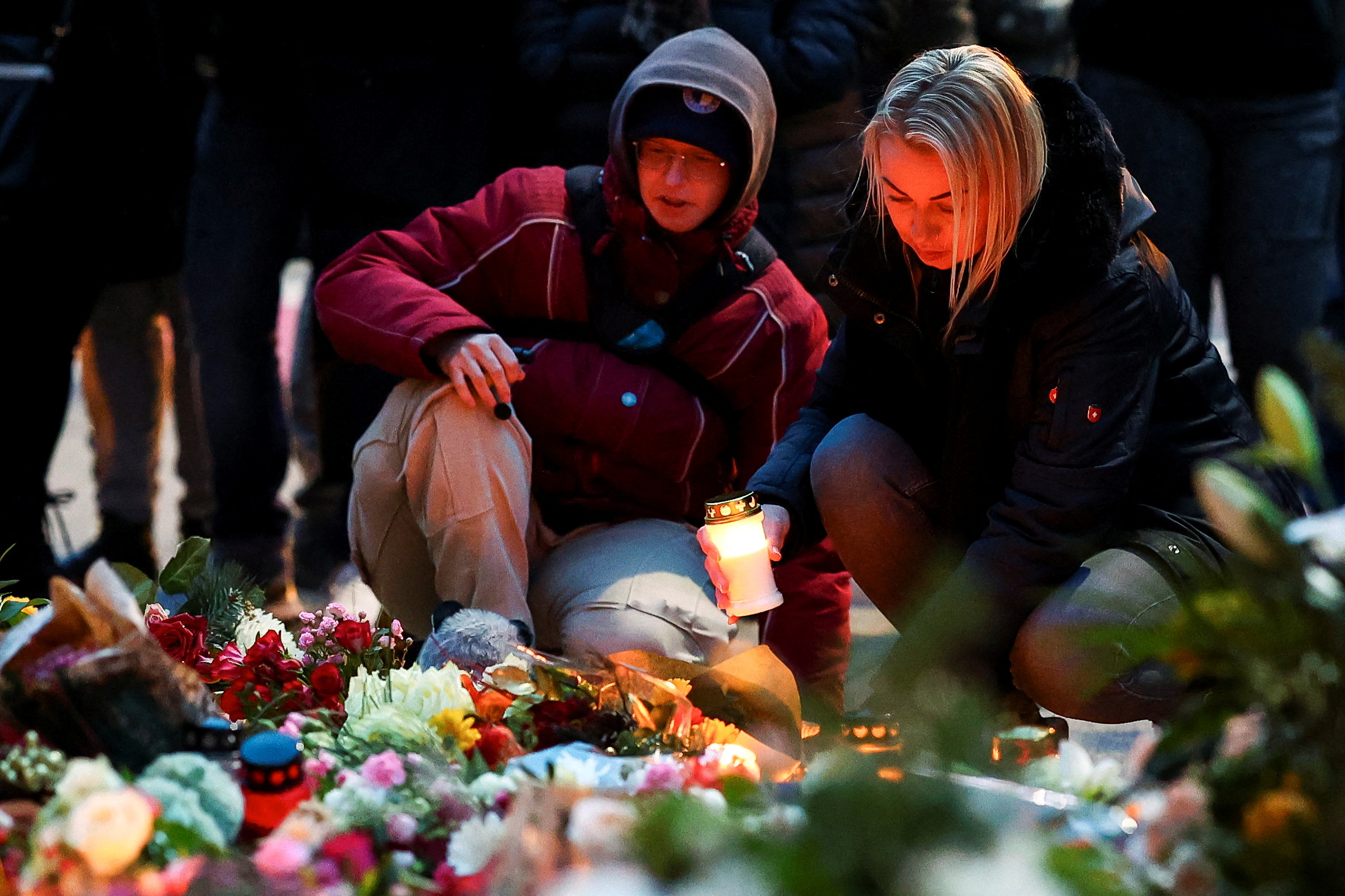 A woman holds a candle as people leave floral tributes to the victims near the site where a car rammed into a crowd at a Magdeburg Christmas market in Magdeburg, Germany December 21, 2024. REUTERS