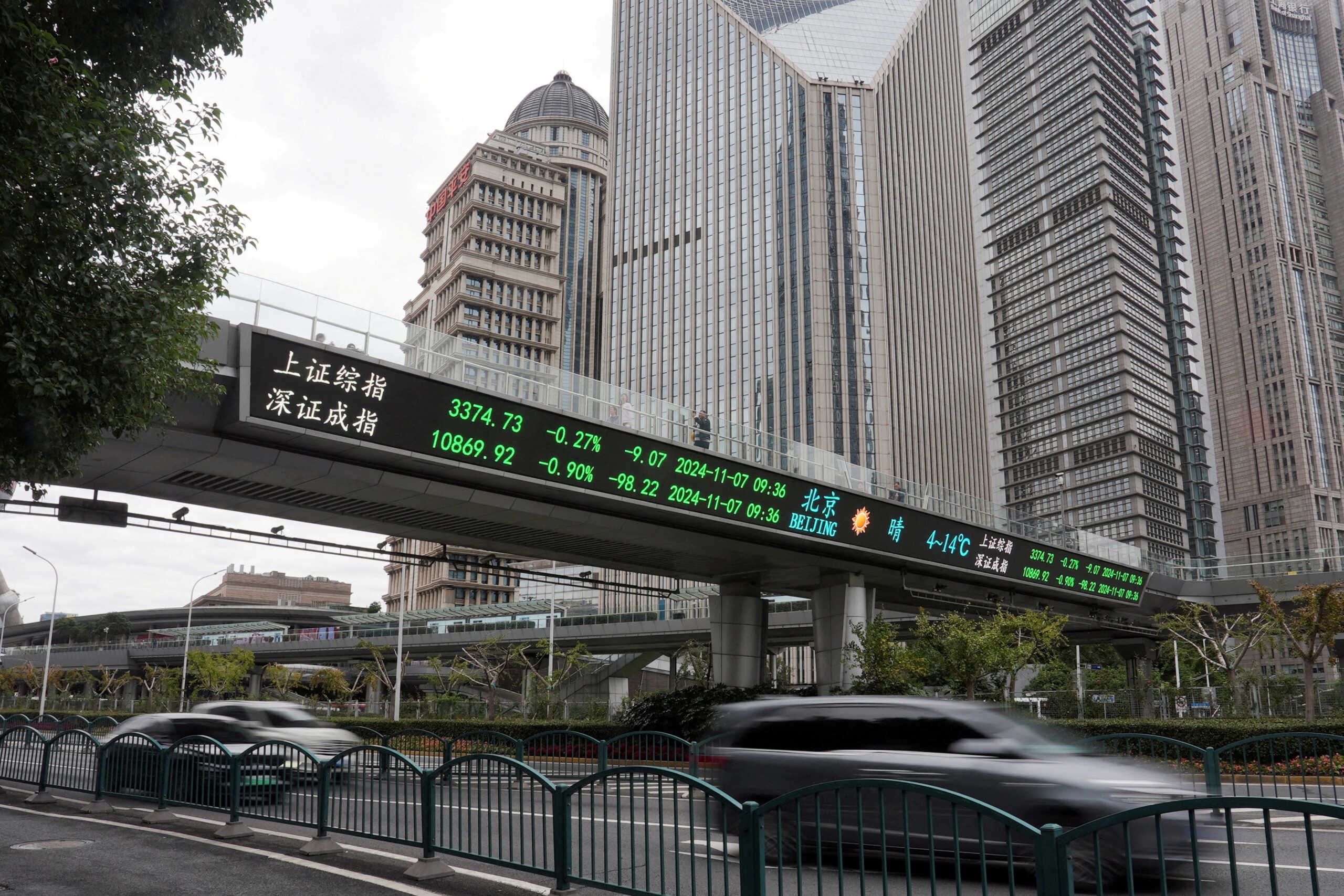 FILE PHOTO: FILE PHOTO: Cars travel past a pedestrian overpass with a display of stock information at the Lujiazui financial district in Shanghai, China, November 7, 2024. REUTERS