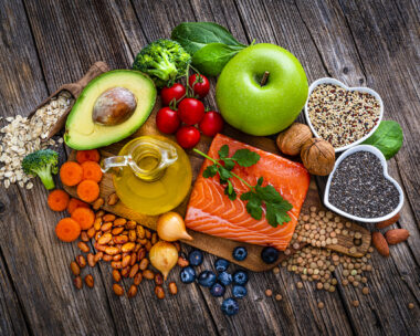 Overhead view of a group of food for heart care and lower cholesterol shot on rustic wooden table. The composition includes salmon, olive oil, chia seeds, quinoa, broccoli, avocado, green apple, oatmeal, spinach, brown lwntil, pinto bean, onion, almonds, walnut, carrot blueberries among others. High resolution 42Mp studio digital capture taken with SONY A7rII and Zeiss Batis 40mm F2.0 CF lens