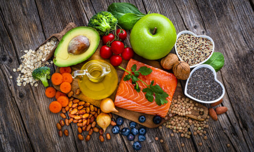 Overhead view of a group of food for heart care and lower cholesterol shot on rustic wooden table. The composition includes salmon, olive oil, chia seeds, quinoa, broccoli, avocado, green apple, oatmeal, spinach, brown lwntil, pinto bean, onion, almonds, walnut, carrot blueberries among others. High resolution 42Mp studio digital capture taken with SONY A7rII and Zeiss Batis 40mm F2.0 CF lens