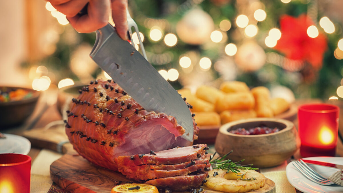 Woman carving glazed ham for holiday dinner