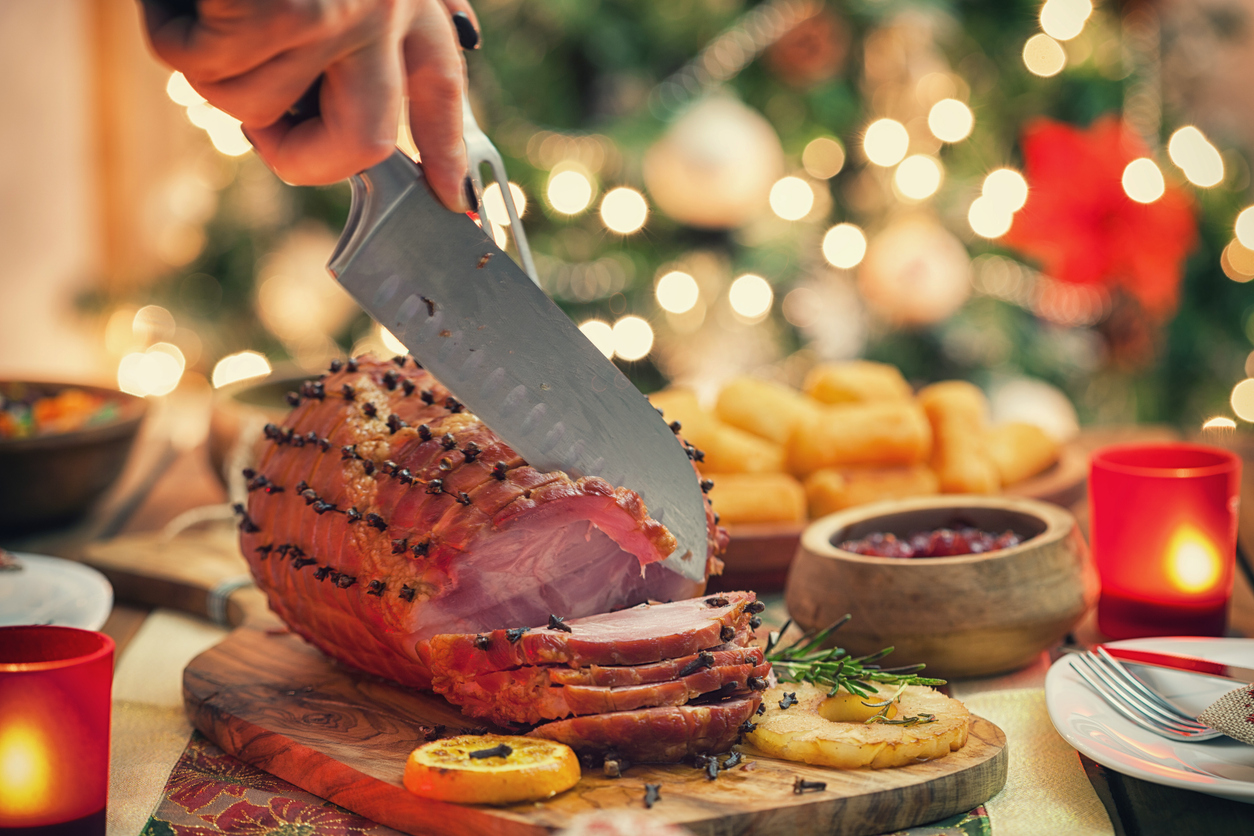 Woman carving glazed ham for holiday dinner