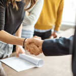 Cropped shot of businessman greeting a young professional around the table in office. Close up of business people shaking hands in office.