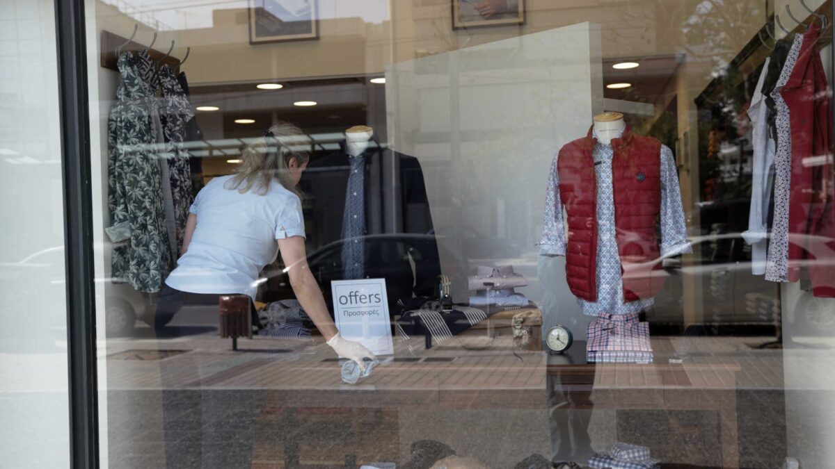 Εργαζόμενη τακτοποιεί βιτρίνα με ρούχα σε κατάστημα