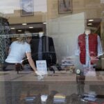 Εργαζόμενη τακτοποιεί βιτρίνα με ρούχα σε κατάστημα