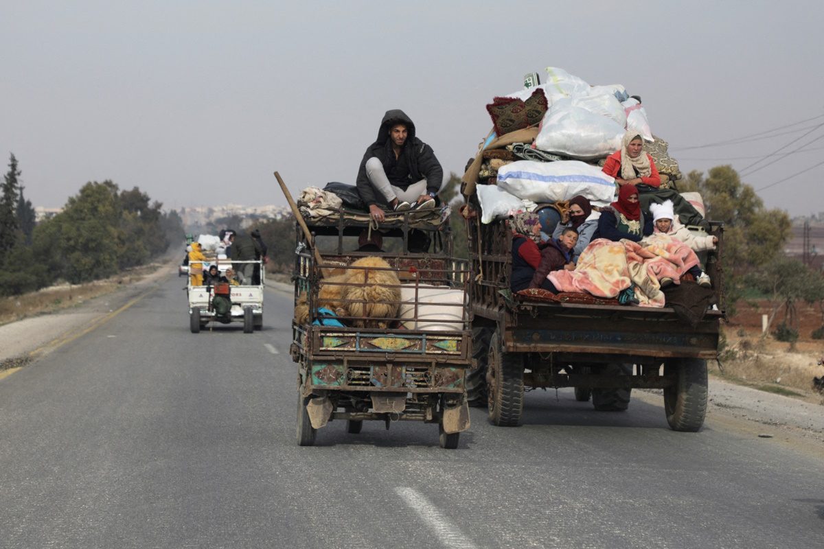 People ride on vehicle with belongings in Hama, after rebels led by HTS have sought to capitalize on their swift takeover of Aleppo in the north and Hama in west-central Syria by pressing onwards to Homs, in Hama, Syria December 6, 2024. REUTERS