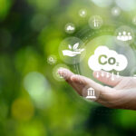 CO2 emission reduction concept in hand with environmental icons, global warming, sustainable development, connectivity and renewable energy