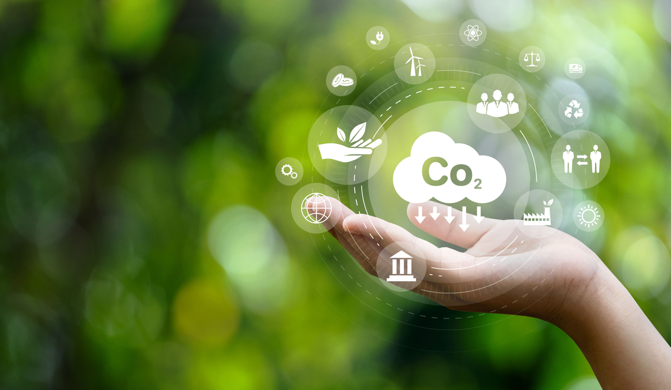 CO2 emission reduction concept in hand with environmental icons, global warming, sustainable development, connectivity and renewable energy