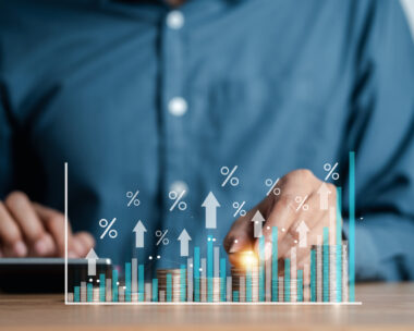 Businessman hand stacking money coins with virtual percentage icons for financial banking increase interest rate, mortgage and property investment dividend value from business growth concept.