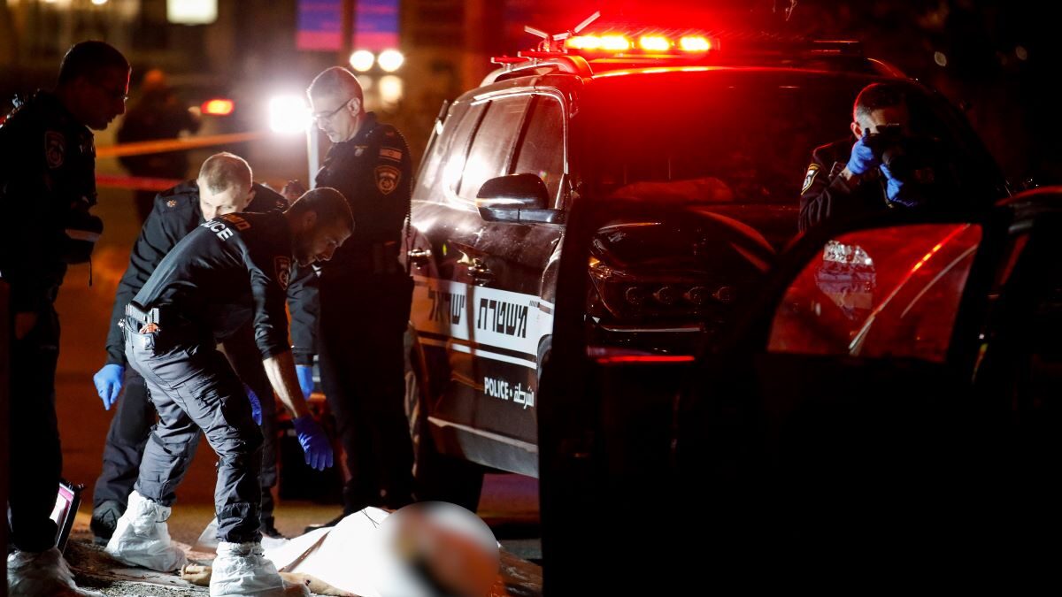 Αστυνομικοί καλύπτουν το πτώμα ενός ύποπτου, στον τόπο της επίθεσης στο Ισραήλ