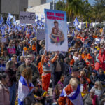 Γυναίκα κρατά φωτογραφία της Σίρι Μπίμπας και των γιων της