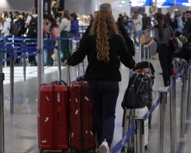 Επιβάτες με βαλίτσες περπατούν σε αεροδρόμιο