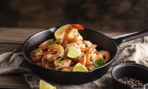 Grilled shrimps with greens and garlic in a pan