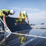 Team of two engineers installing solar panels on roof
