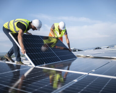 Team of two engineers installing solar panels on roof